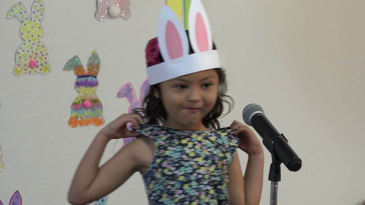 Young girl in paper bunny ears beside a microphone and rabbit drawings
