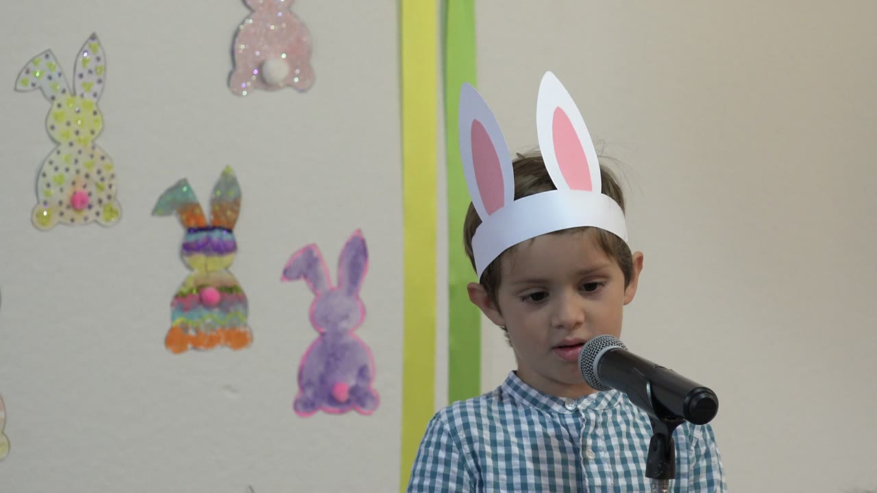 Child in bunny ears standing beside a microphone