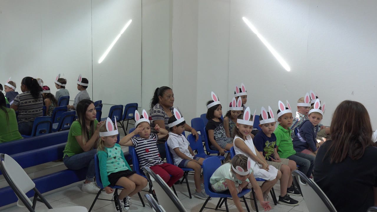 A similar audience-side view shows children in rabbit ears seated in blue chairs while adults stand and sit along the wall in Cabo San Lucas, Mexico.