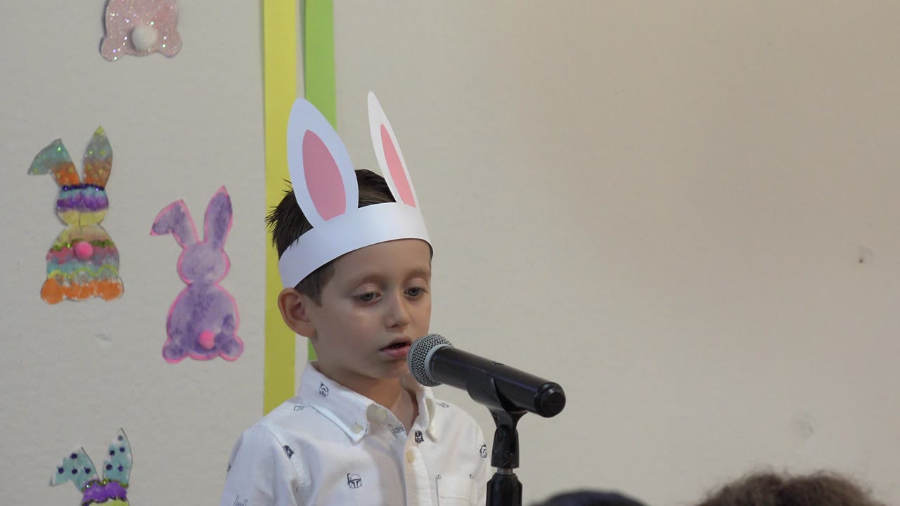 The child in Cabo San Lucas faces the microphone with a focused expression, framed beside colorful bunny cutouts on the wall.