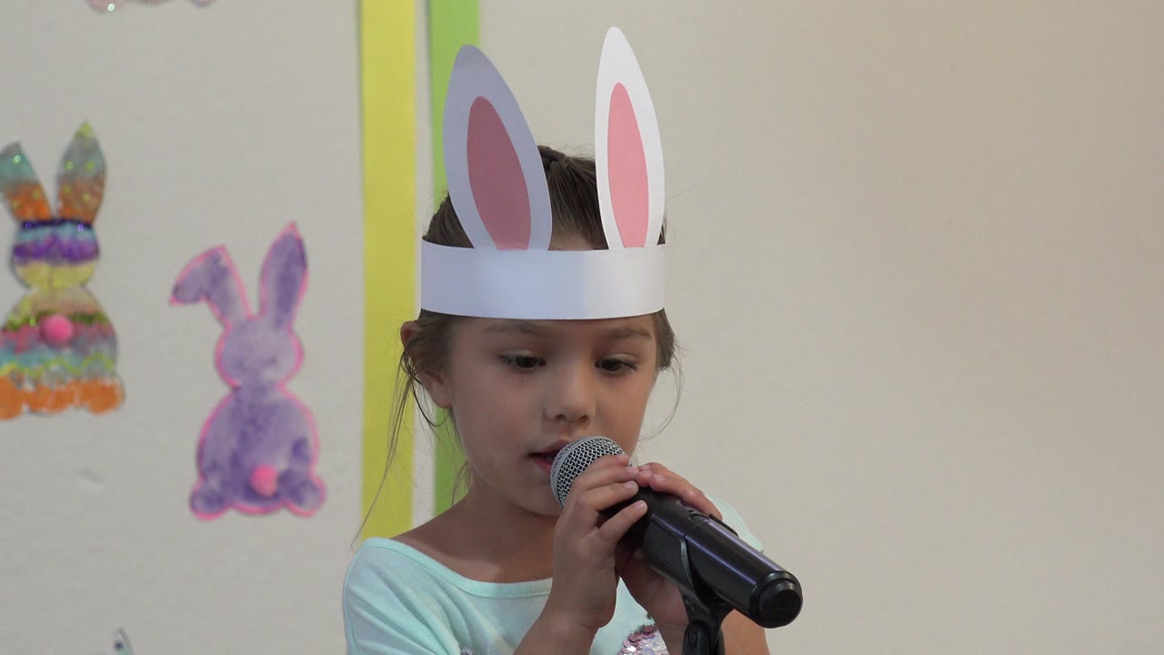 Young girl in bunny ears speaking into a microphone
