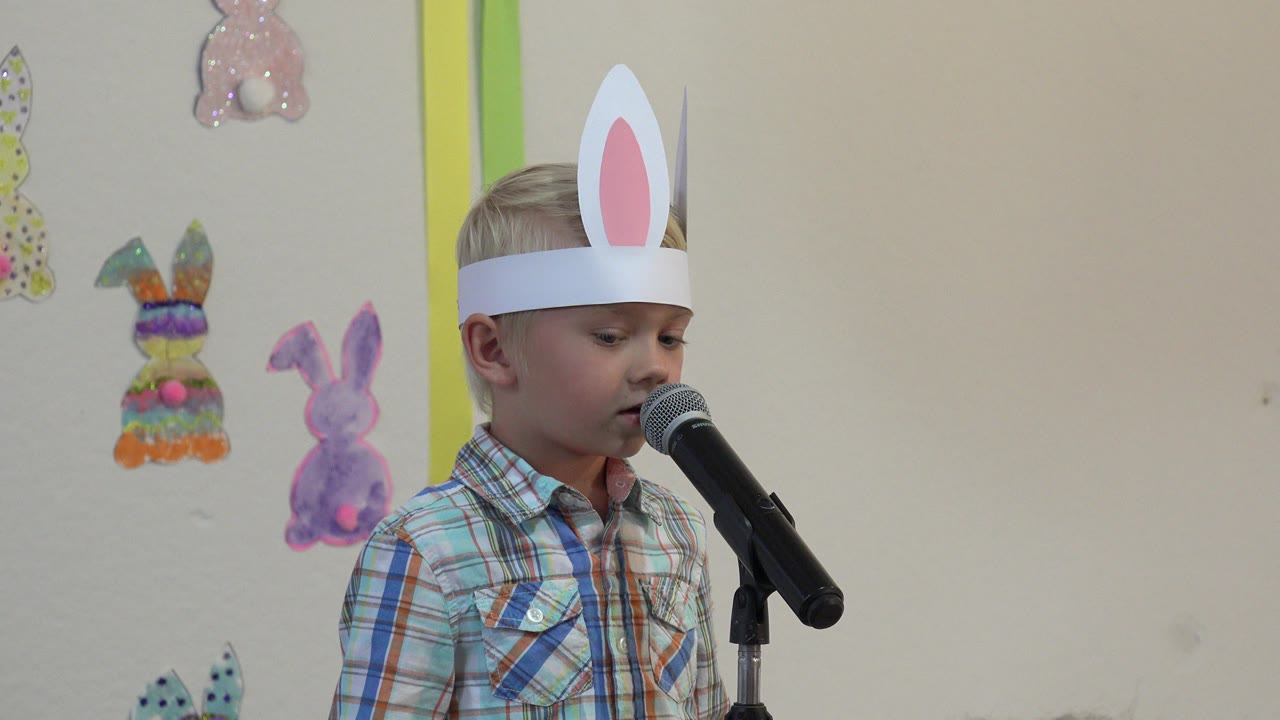 The boy faces slightly downward toward the microphone, with pastel rabbit decorations visible on the wall behind him in Cabo San Lucas, Mexico.