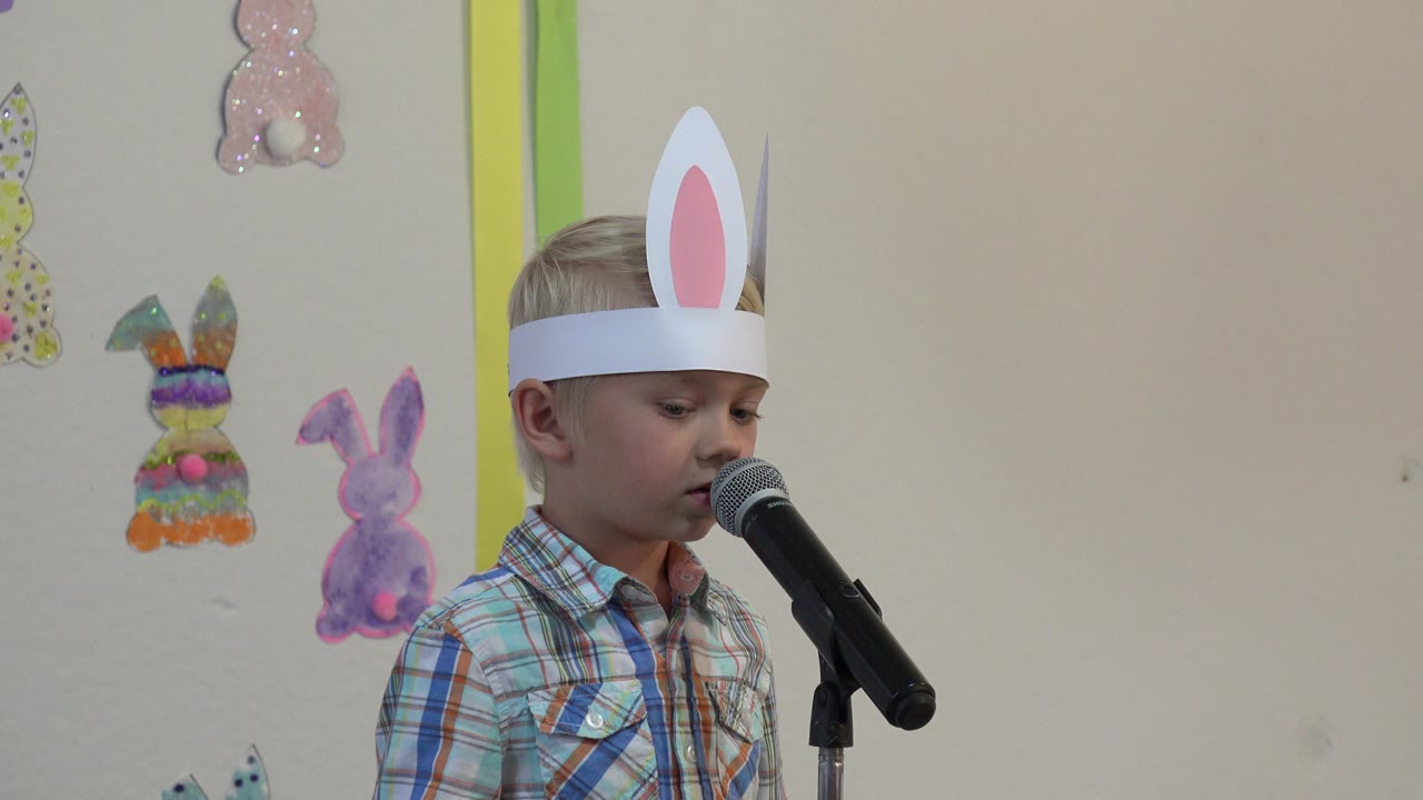 Young boy in bunny ears speaking into a microphone.