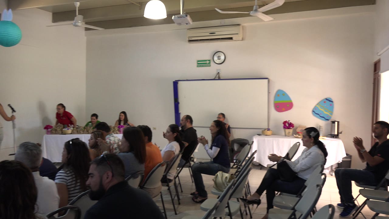 Adults seated in folding chairs during an indoor gathering.