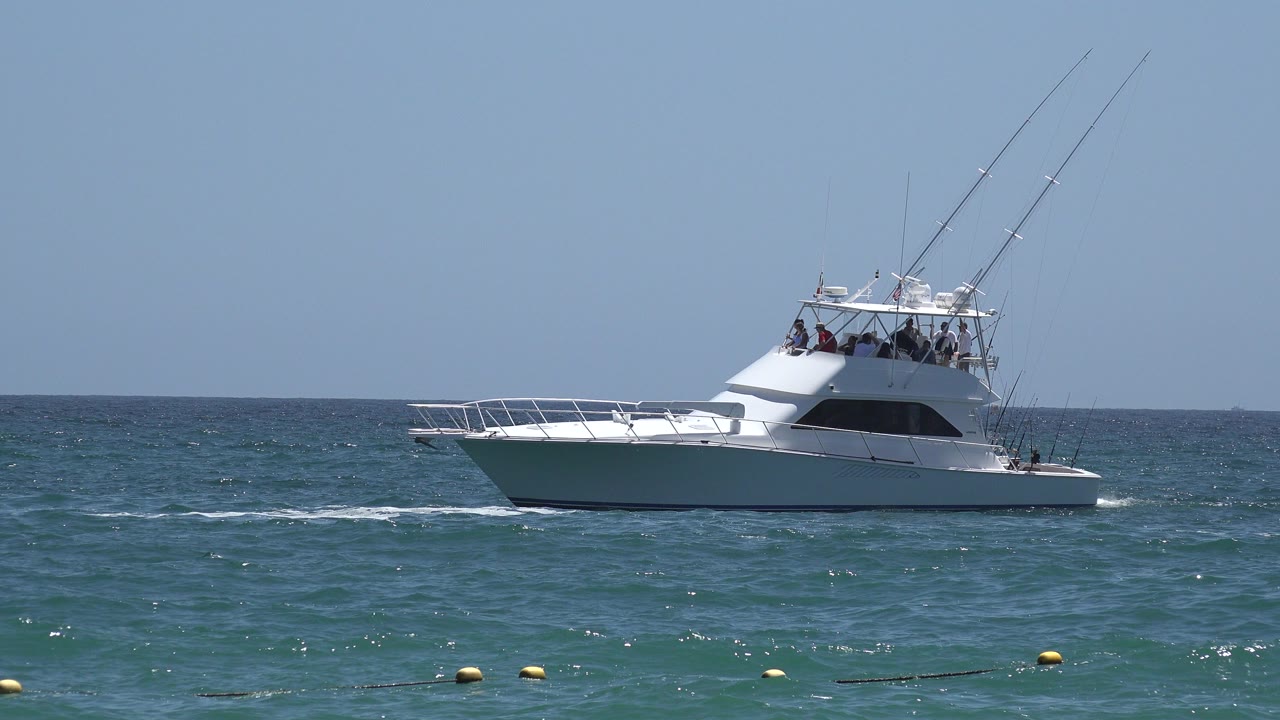 White sportfishing yacht on blue-green ocean under clear sky.