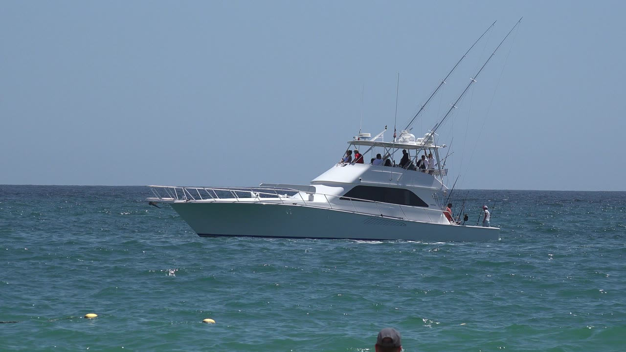 White sport fishing yacht on blue-green ocean under clear sky.
