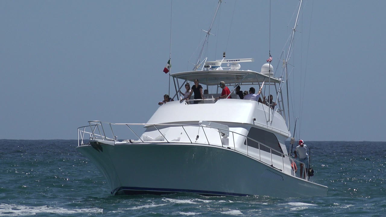 Large white yacht approaching over blue ocean water.