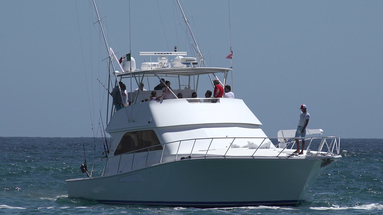 White sportfishing boat on choppy ocean with people aboard.