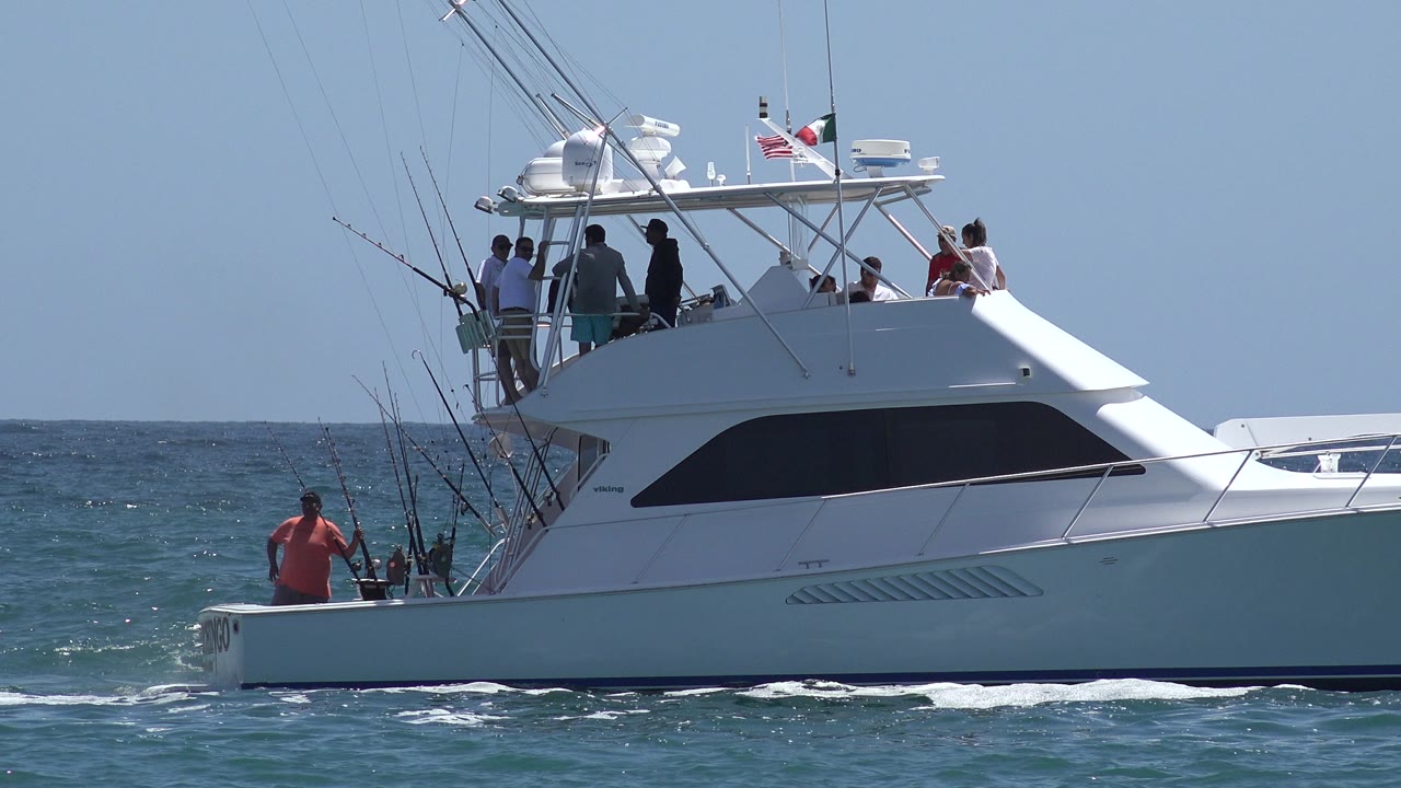 Sportfishing boat moving across choppy water with people aboard.
