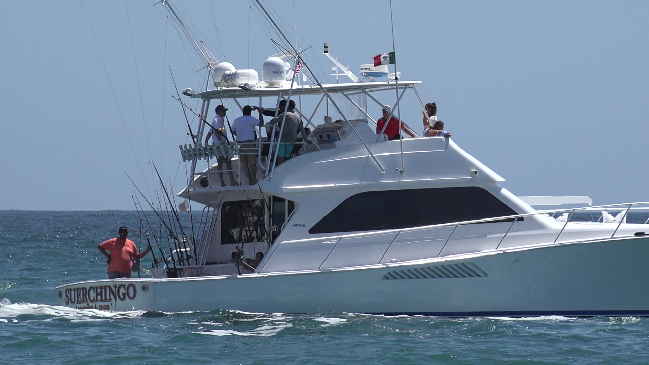 White sportfishing boat with passengers on blue ocean.