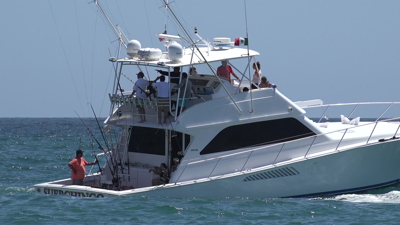 White sportfishing boat on choppy blue water with passengers aboard.
