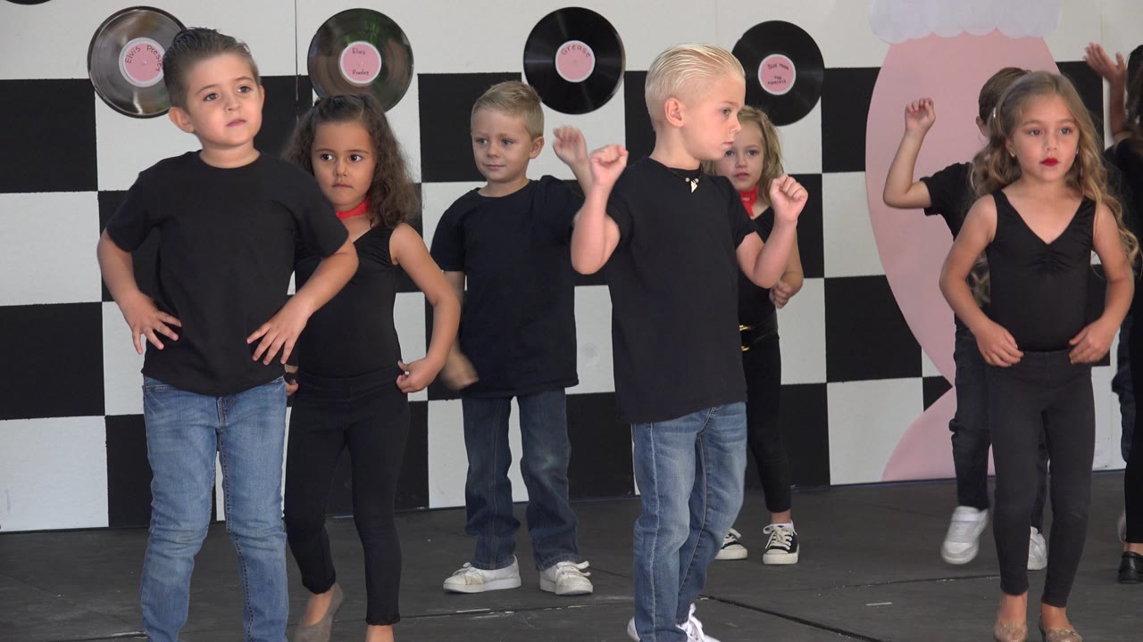 Children shift positions during a stage dance routine.