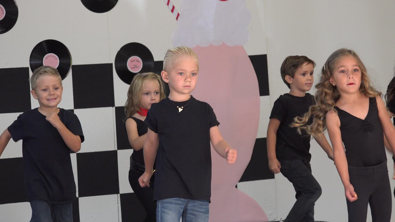 Children dancing with a girl in black dancewear near the front