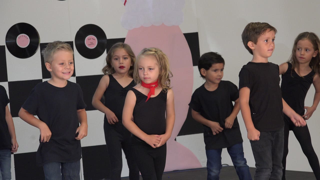 Group of children standing and dancing on a decorated stage.
