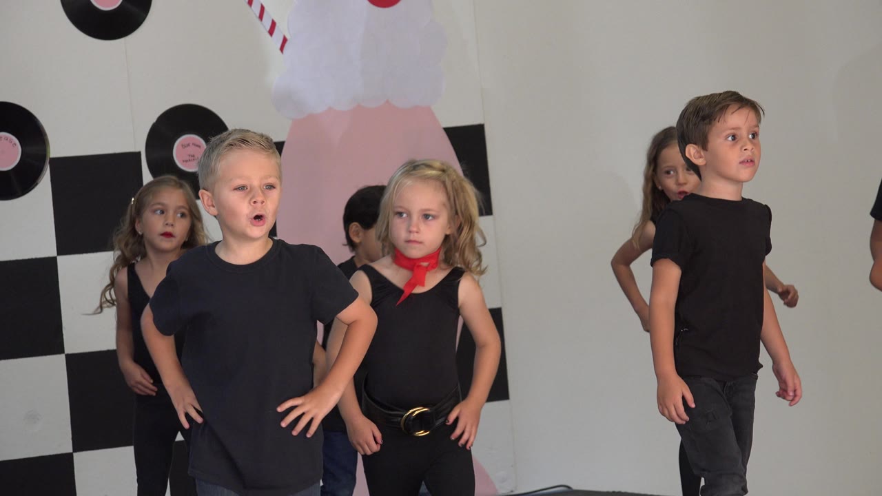 Children face forward during a dance recital moment.