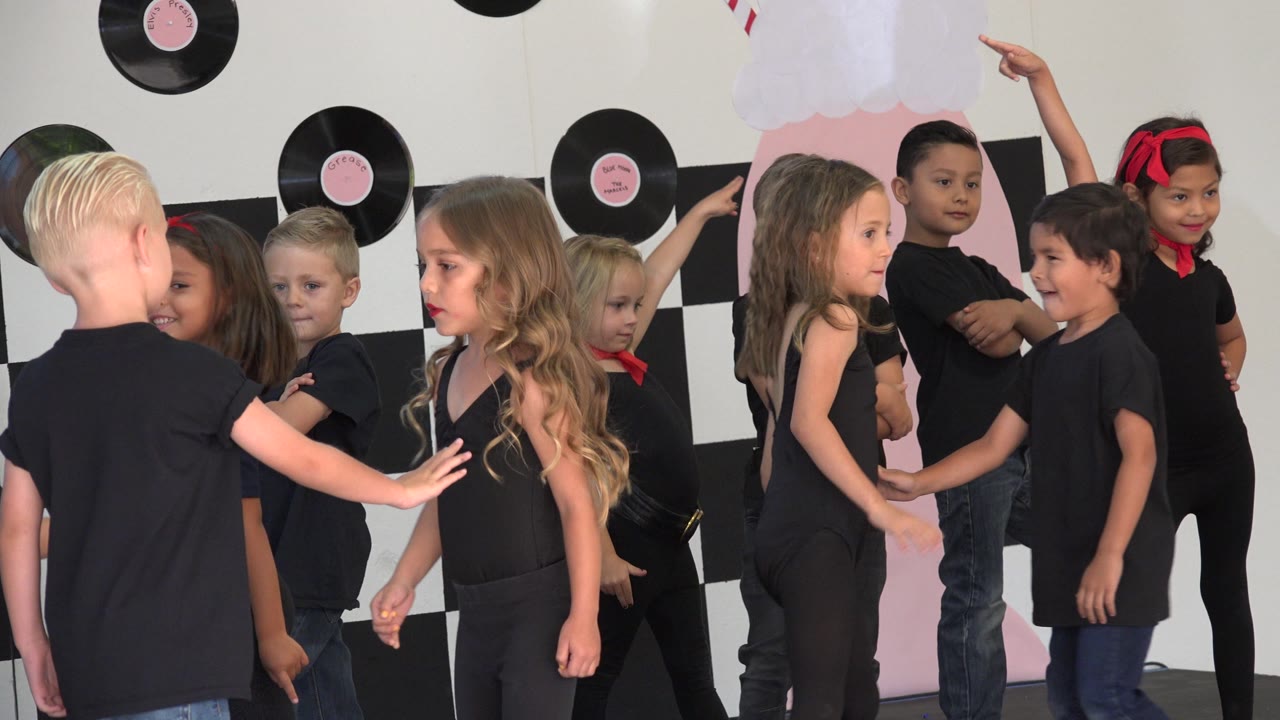 Children on stage with one child pointing upward.