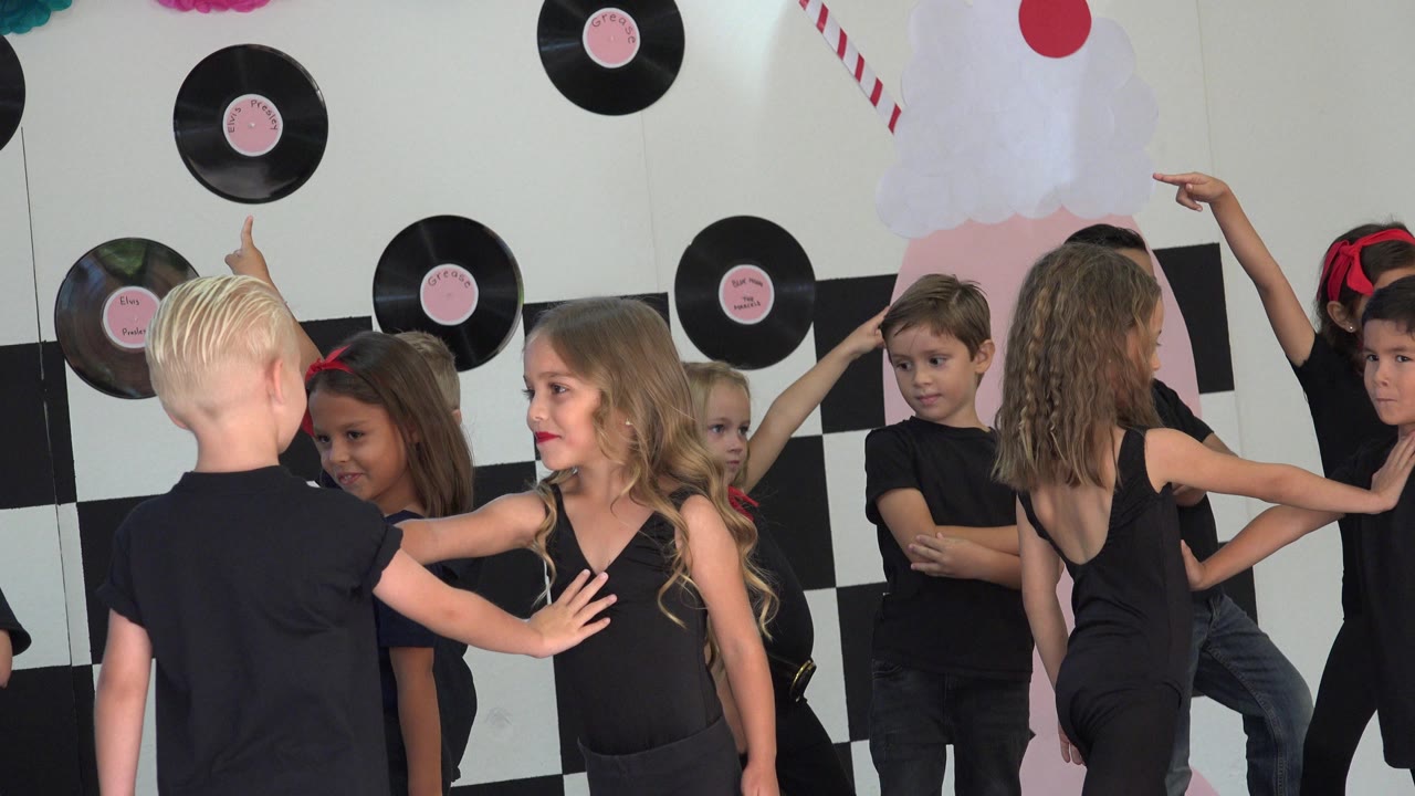 Children in black outfits posing in front of record decorations.