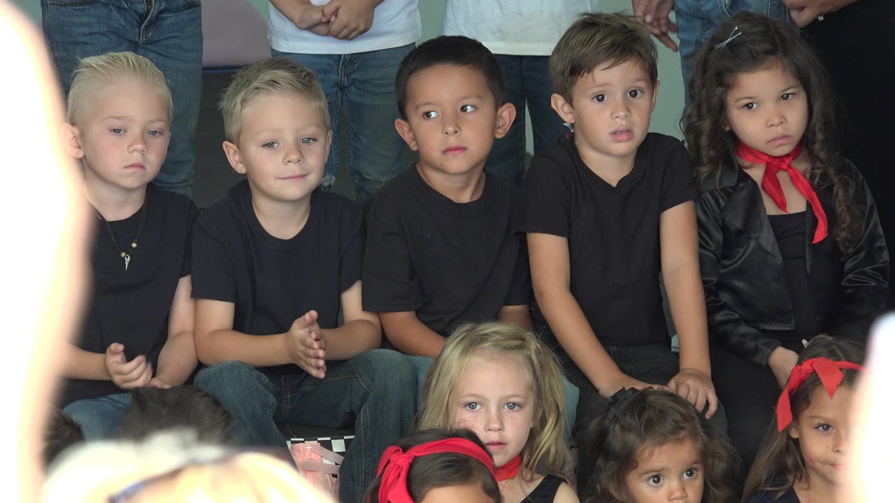 At 0:01 in Cabo San Lucas, Mexico, the same seated children remain in view as a bright out-of-focus foreground shape partially covers the left side of the frame.