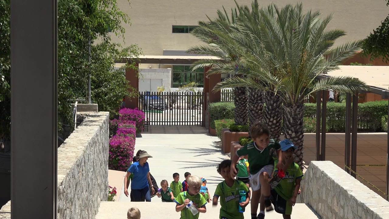 Children with water bottles climbing a walkway after soccer.