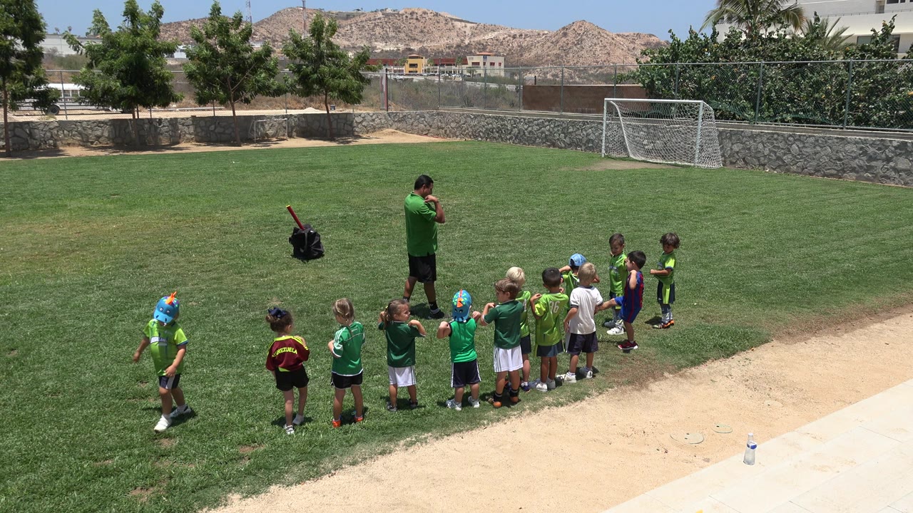 Coach and young children gathered on a soccer field.