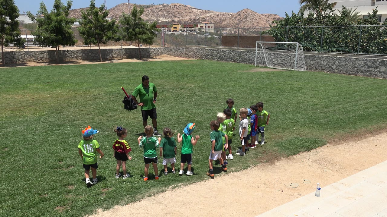 Coach and children gather closer together on the soccer field.