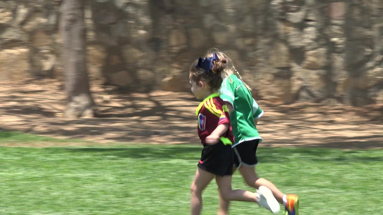 Two girls running hand-in-hand across grass.