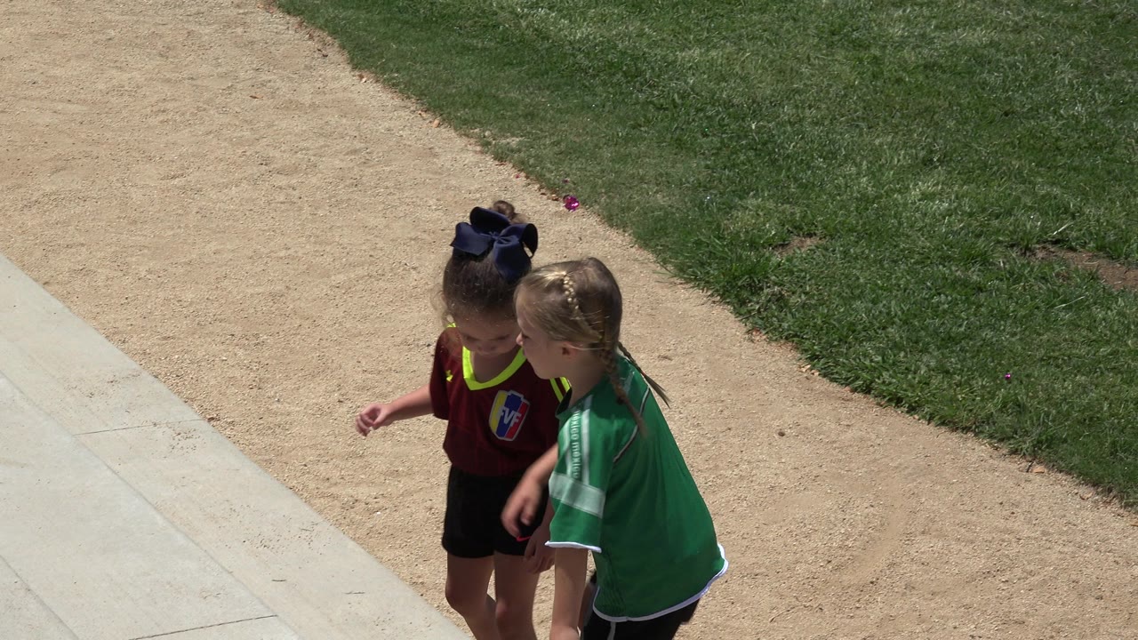 Two girls in green and red sports jerseys on outdoor steps.