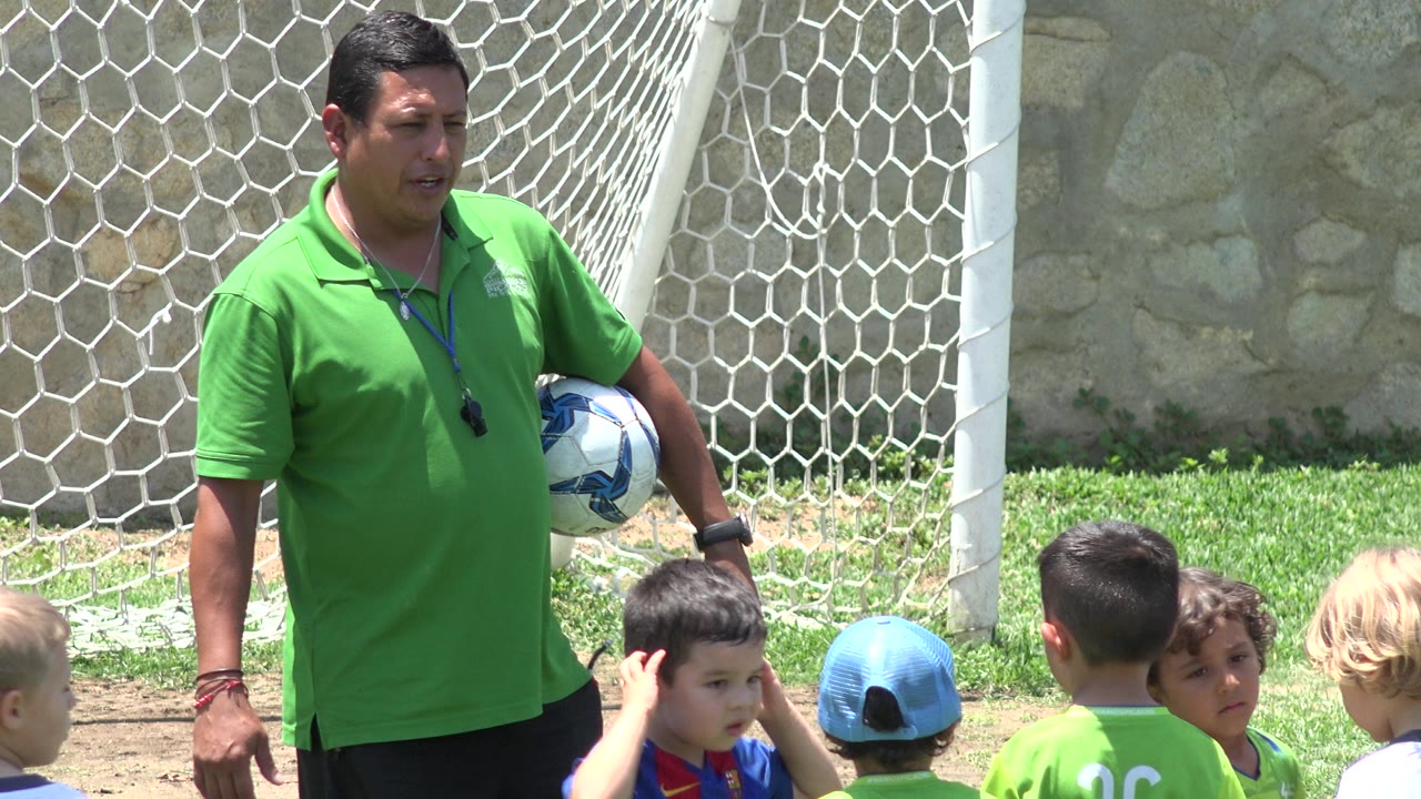 Soccer coach speaking with children beside the goal net