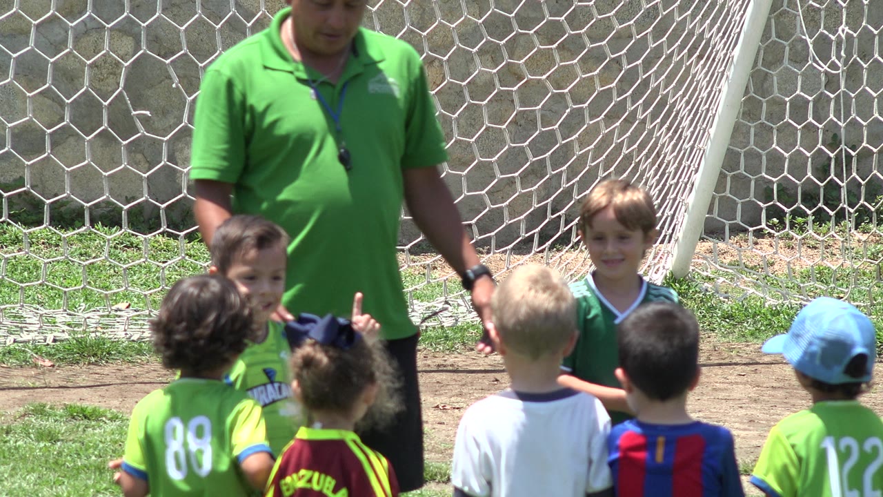 Coach looks down at children gathered in front of a goal.