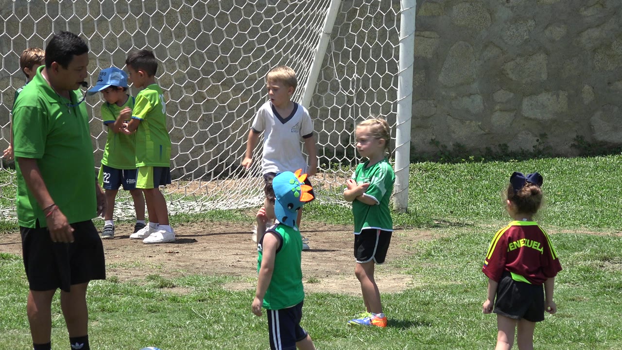 In Cabo San Lucas, Mexico, a small group of children in soccer clothing gathers in bright sun near the net, with one child in a blue cap beside the goal.