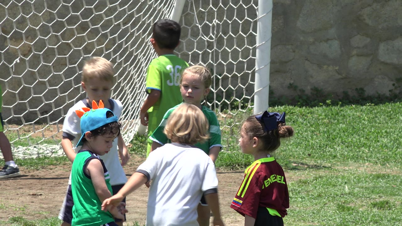 Children gather near the goal as one child turns away from camera.