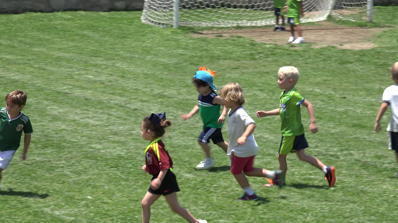 Kids spread out while running on the grass field.