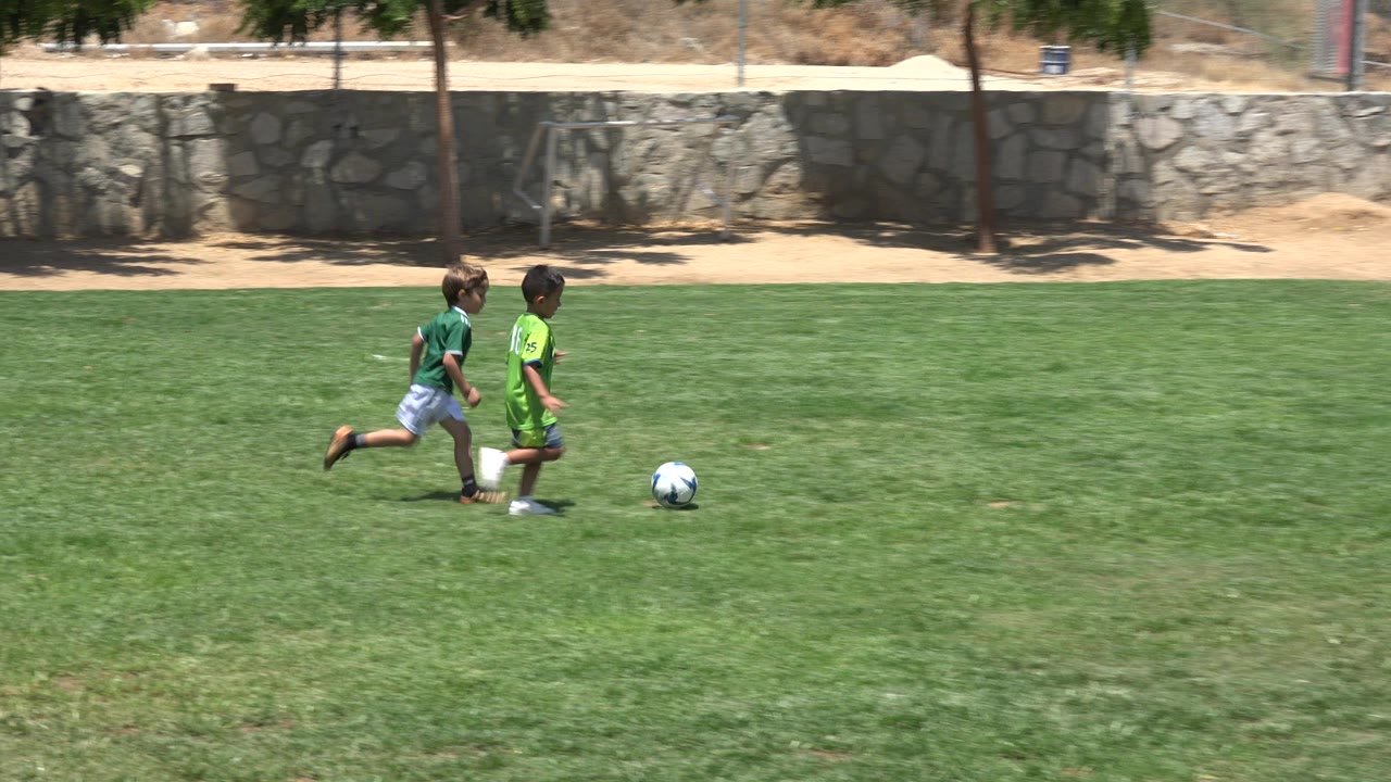 One second in, the two young players remain side by side as the soccer ball rolls ahead on the open grass field in Cabo San Lucas.