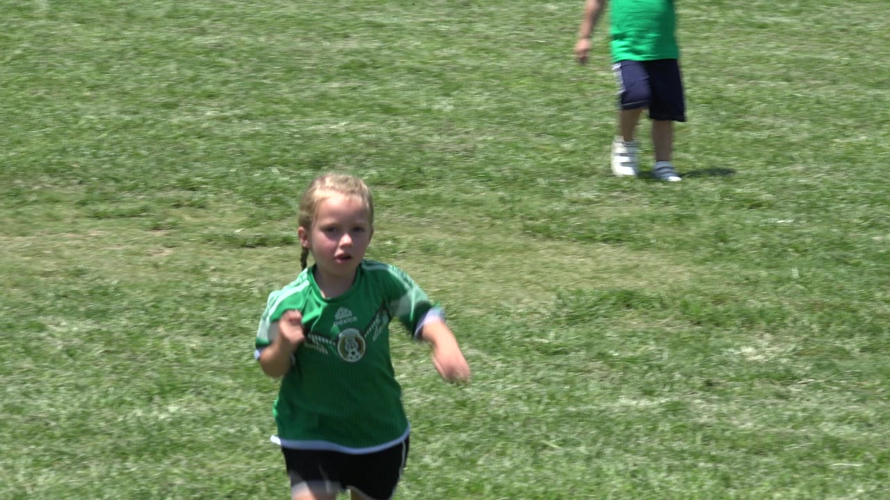 Girl facing camera while running on a grassy field.