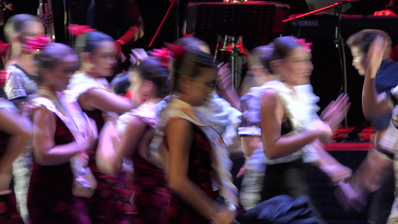 Girls dance in a tight cluster on stage.