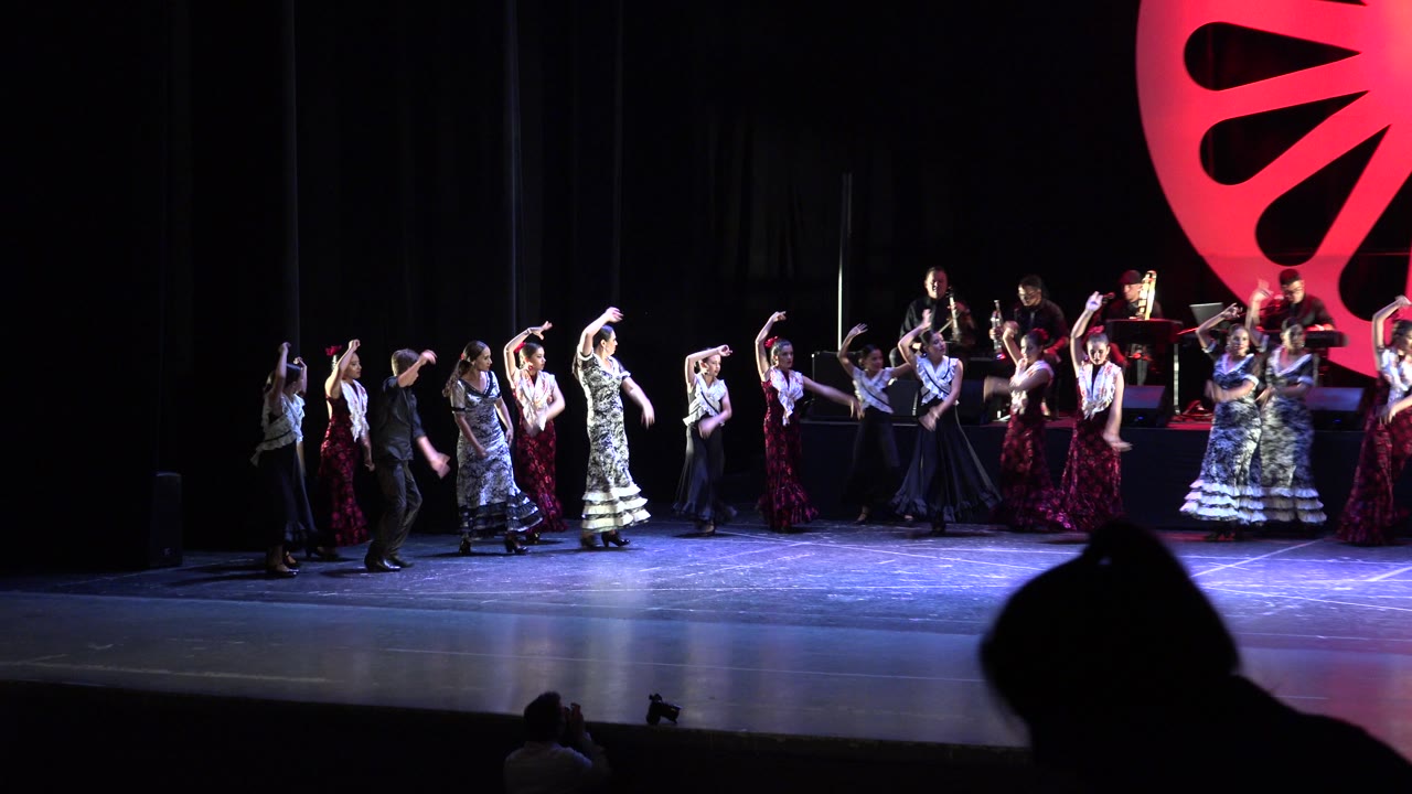 Stage dancers begin moving toward the right side of the performance area.