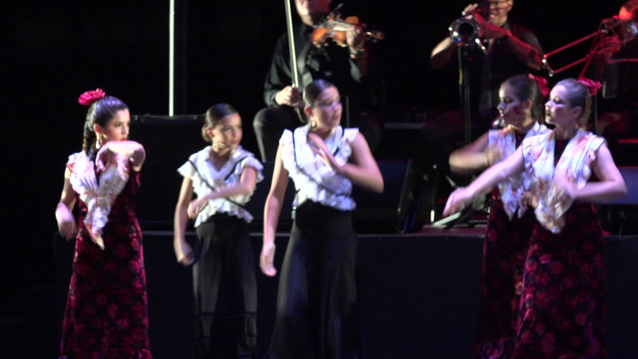 Young dancers on a stage with musicians behind them.