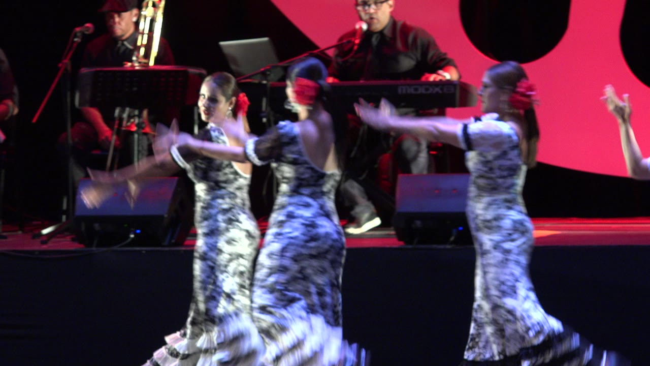 Dancers turn across the stage as the keyboardist remains in the background.
