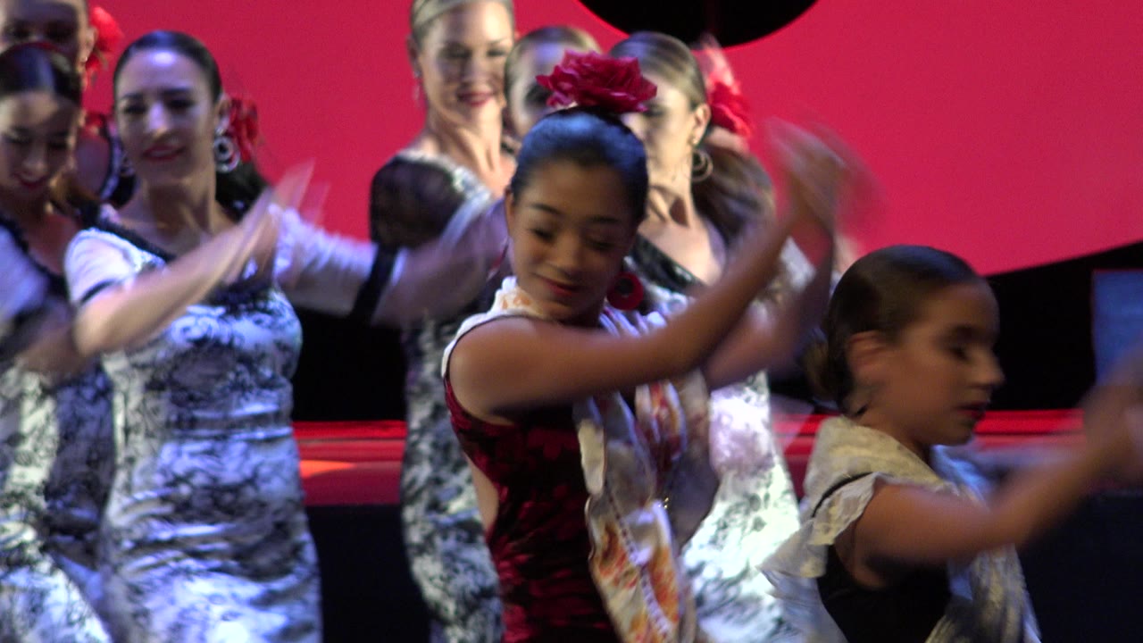 Young dancers raise their arms during a stage performance.