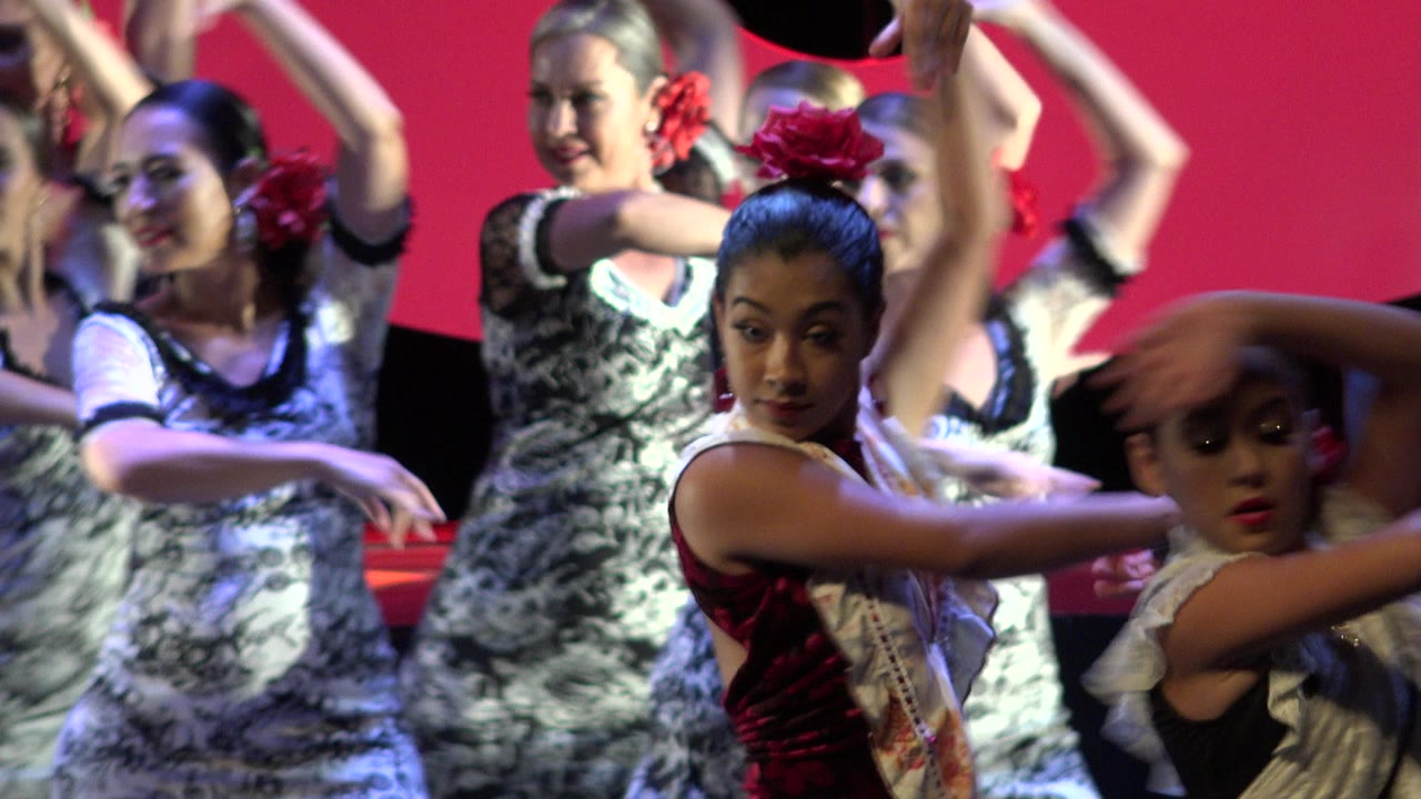 A close view of the Cabo San Lucas dance routine shows front performers crossing their arms while other women dance in formation behind them.