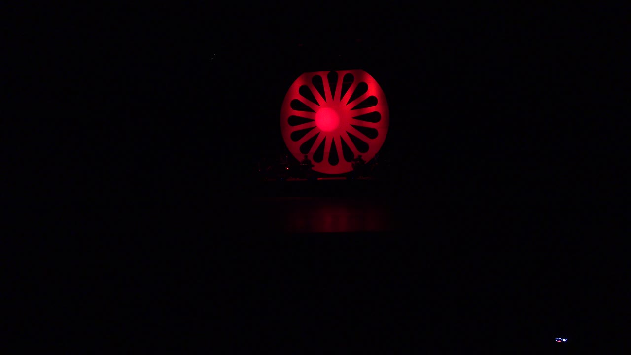 A red circular stage light glows near the top of a dark Cabo San Lucas performance stage, with no visible people in this frame.