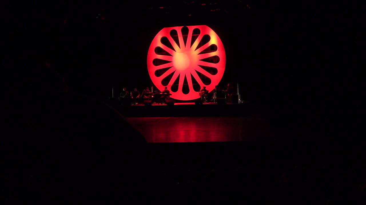 At one second, the Cabo San Lucas stage remains wide and dark, with the red circular prop glowing above instruments and faint silhouettes along the platform.