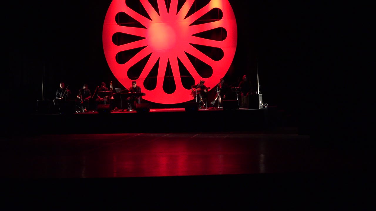 Wide dark concert stage with a glowing red circular wheel backdrop