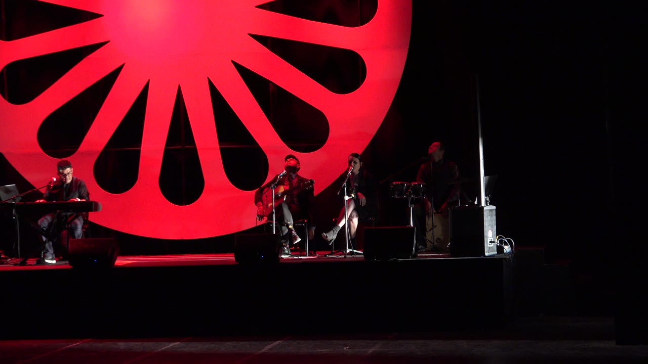 Band on a dark stage beneath a large red circular backdrop.