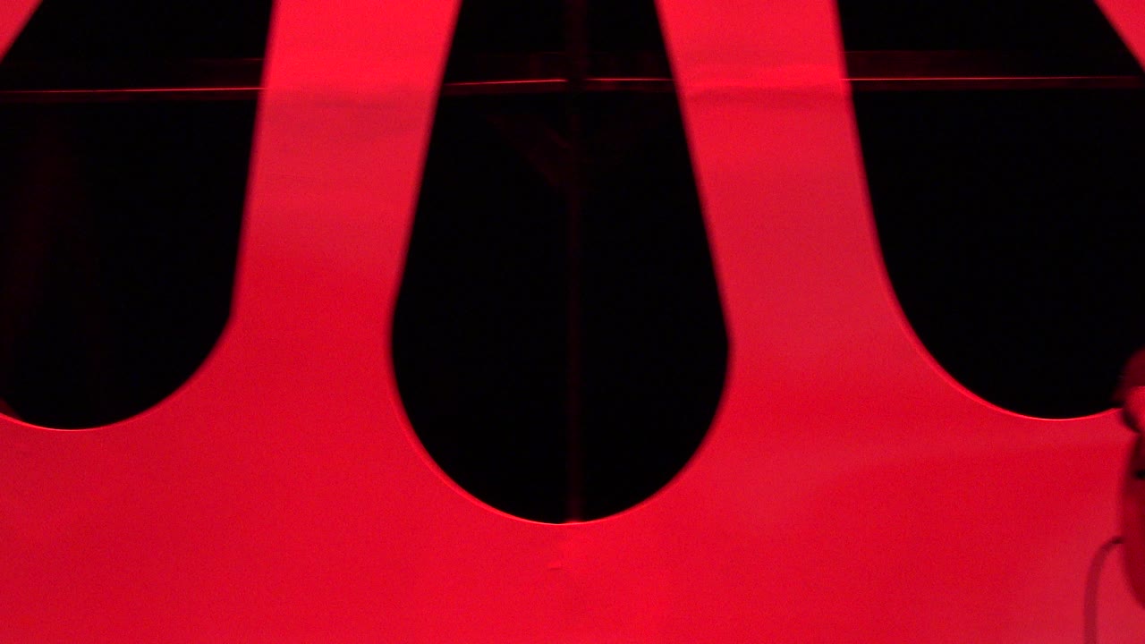Second frame shows the same red indoor stage backdrop in Cabo San Lucas, with dark openings and no visible people.