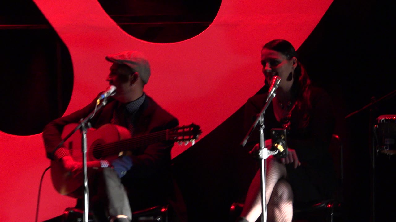 Guitar player and singer framed against red stage graphics