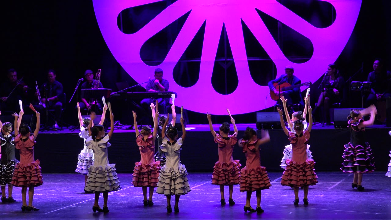 Children continue a group dance in front of musicians.