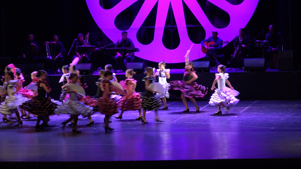Children move across the stage during a group dance.