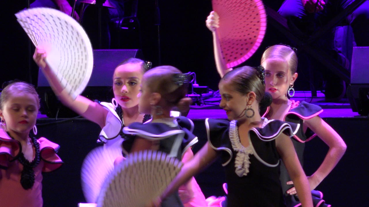 At 0:01 in Cabo San Lucas, Mexico, children in ruffled black, pink, and white costumes shift across the frame with white fans raised and lowered.