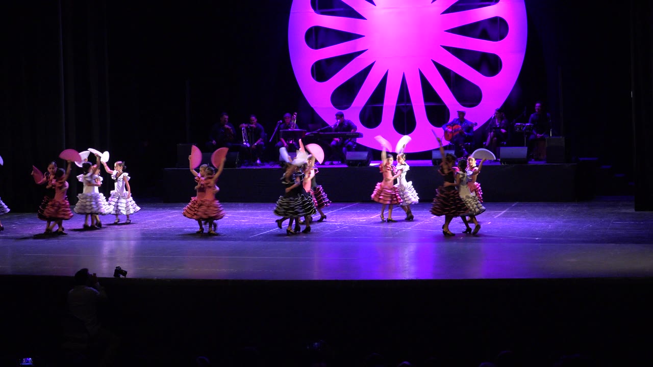 Young girls dancing on a purple-lit stage with fans